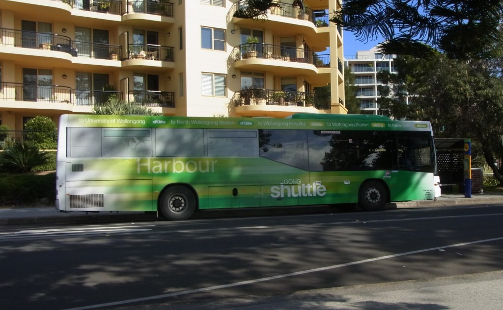 There's a bus stop in front of this beautiful apartment building.