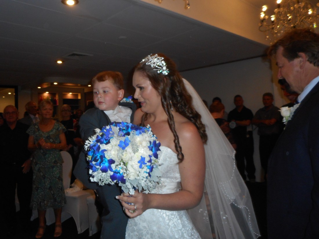 Here comes the bride carrying three year old Lucas. The bride's father on the right.